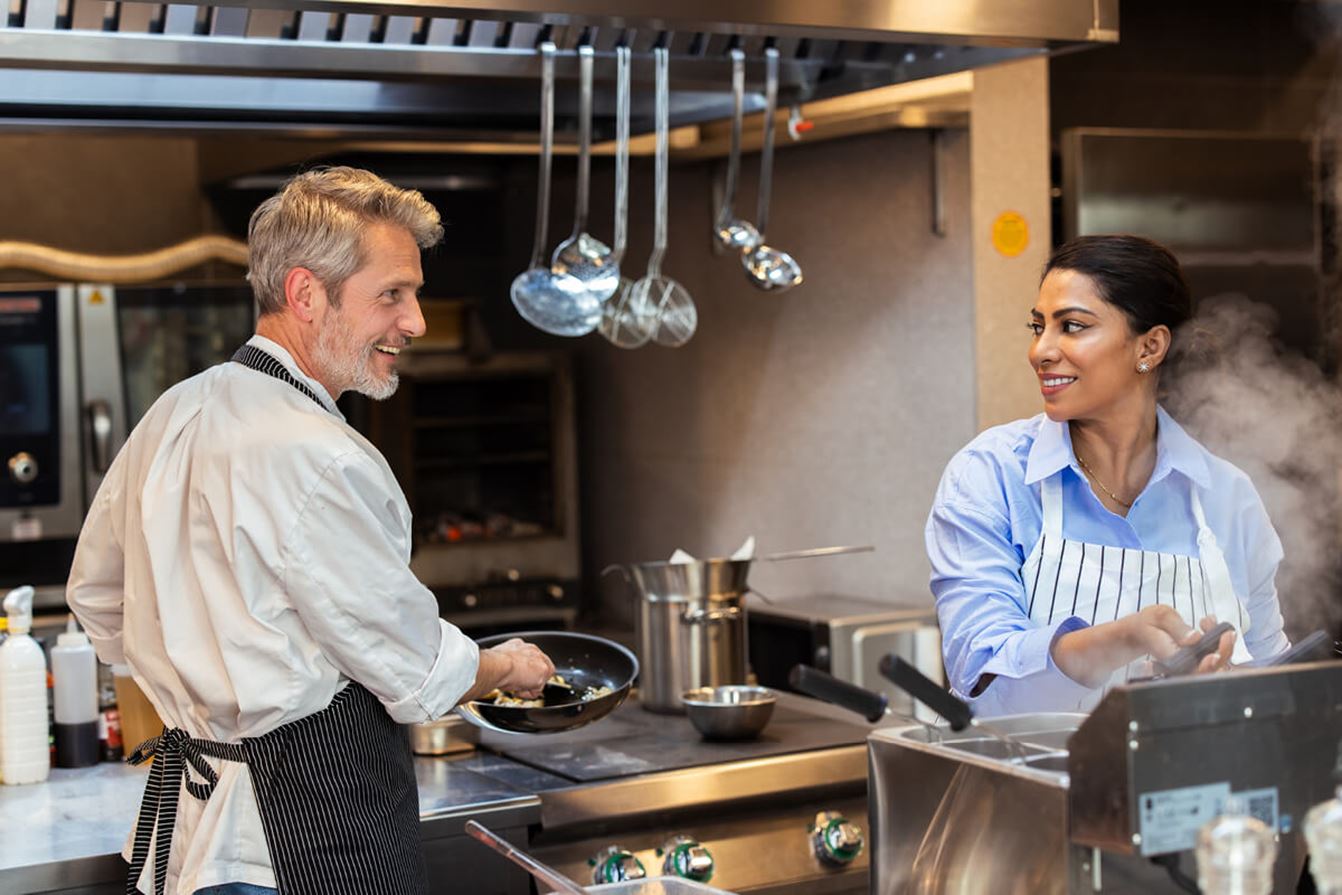 Två personer lagar mat i restaurangkök.