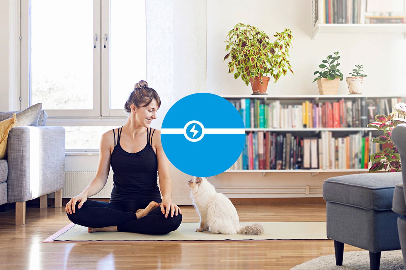 Kvinna sitter på en yogamatta i vardagsrummet och ler mot en katt bredvid sig. En blå symbol för fastpris visas i mitten av bilden.